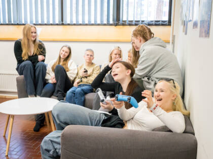Nuoria Kaarinan kirkon pelihuoneessa sohvalla ja pelaamassa PS5