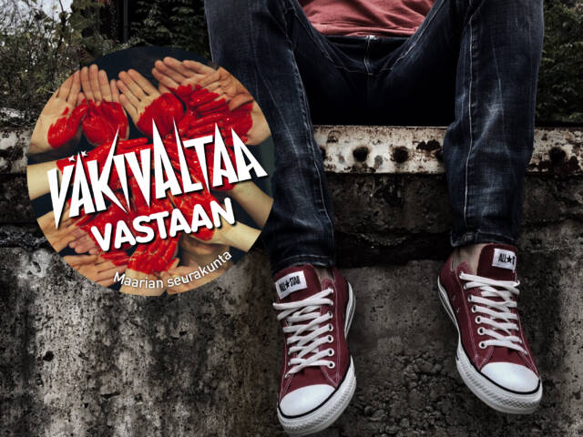 Nuori istuu aidalla, tennarijalat. Väkivaltaa vastaan teksti kämmenien päällä joihin maalattu punainen sydän.