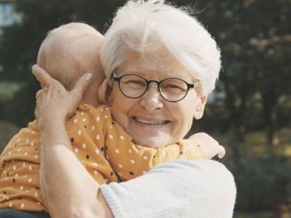 En äldre dam håller en baby i sin famn.