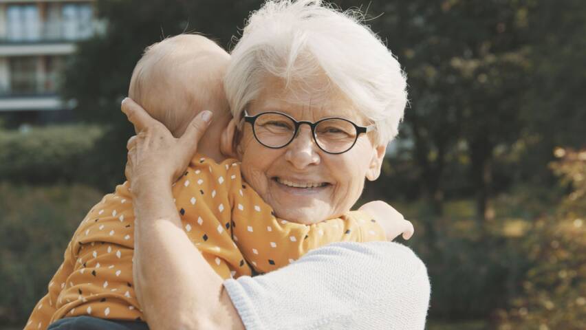 En äldre dam håller en baby i sin famn.