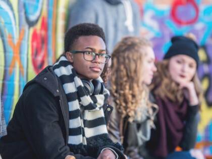 Young people are sitting in front of a graffiti wall.
