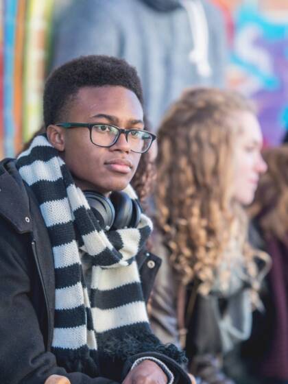 Young people are sitting in front of a graffiti wall.