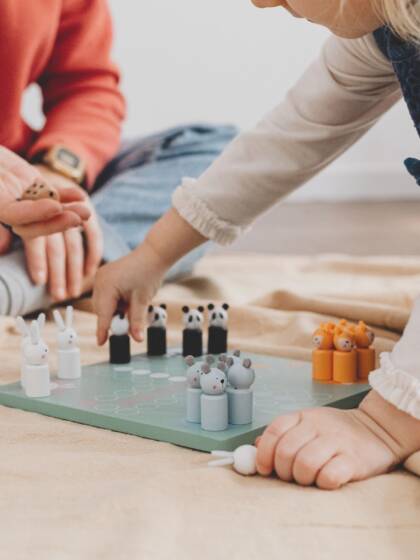 Ett barn och en vuxen spelar ett brädspel.