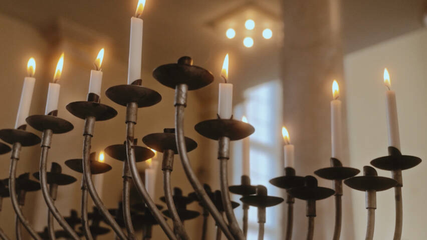 En metalljusstake med åtta tända ljus.