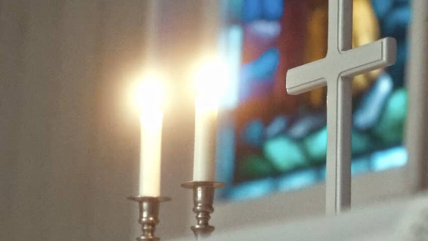 Alttarilla kaksi palavaa kynttilää ja risti.