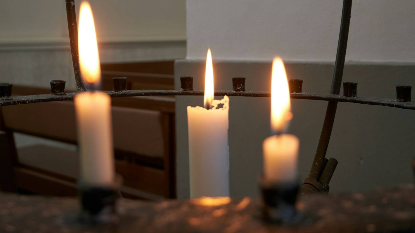 Kolme palavaa kynttilää lähetyskynttelikössä.