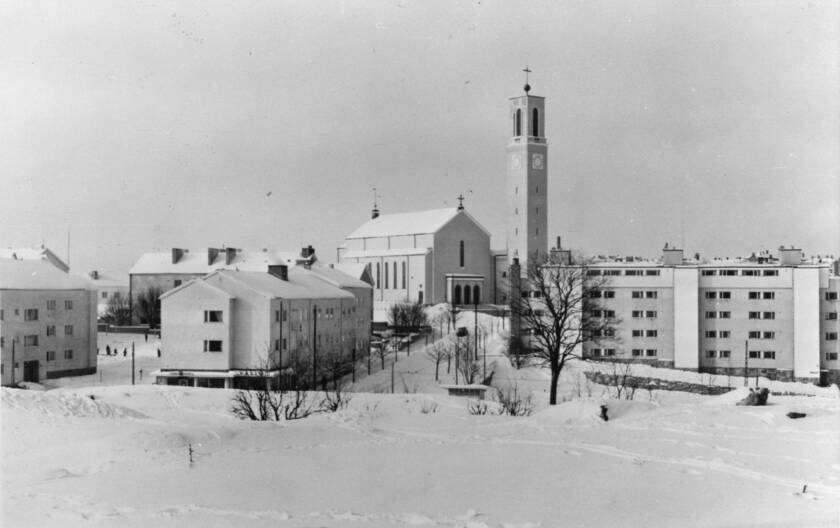 Talvinen maisema Martinkirkosta, jossa on lumisia katuja, kirkko ja asuinrakennuksia. Taustalla näkyy puu ja kirkontorni.