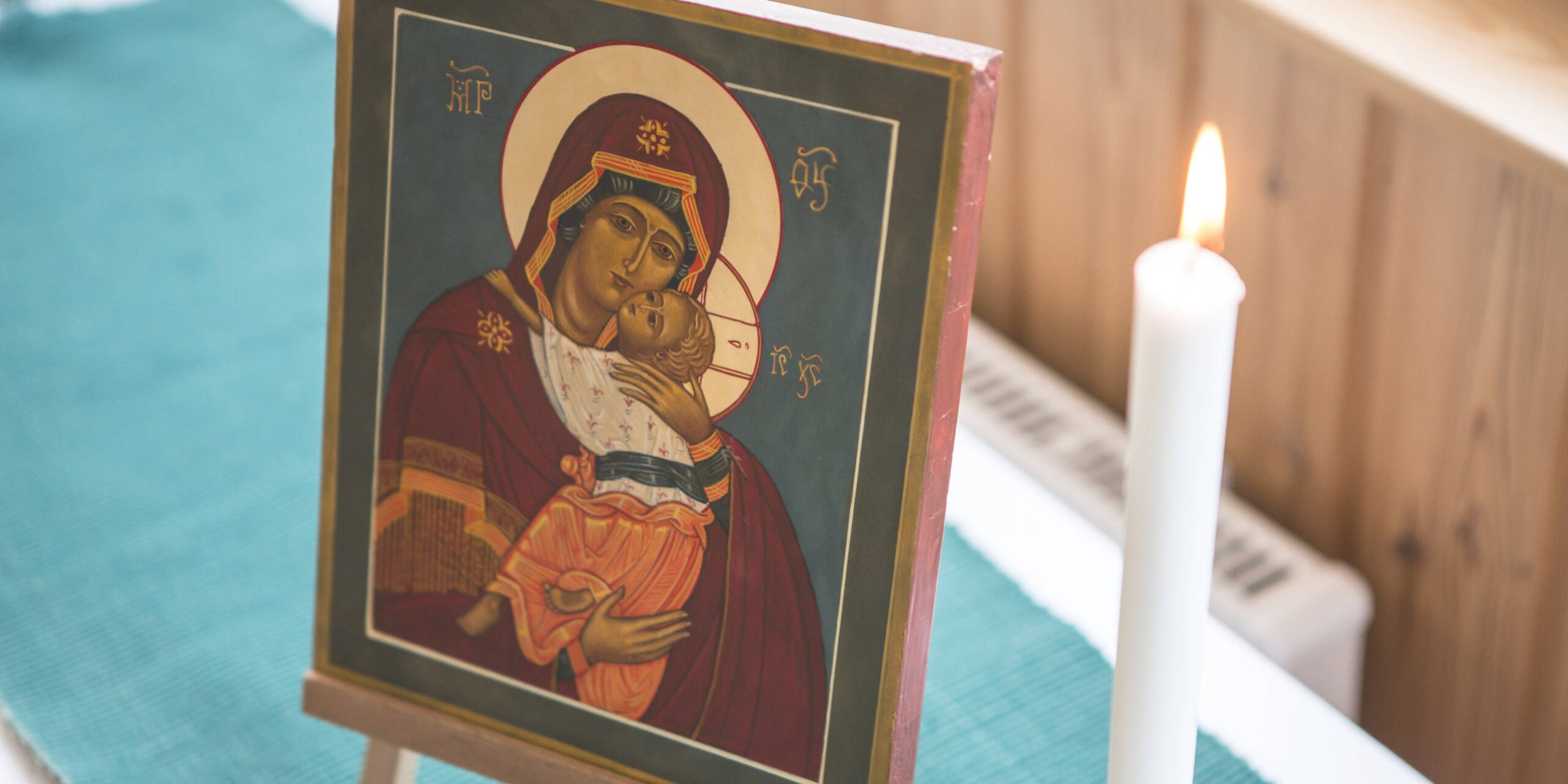 Ikoni, jossa on neitsyt maria ja Jeesus-lapsi, ja kynttilä ikonin vieressä.