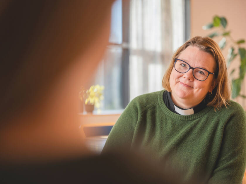 Pappi katsoo hymyillen keskustelukumppaniaan.