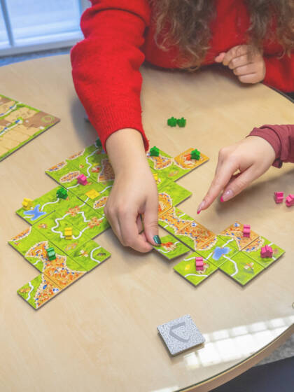 Kolme ihmistä pelaa Carcassone-lautapeliä.