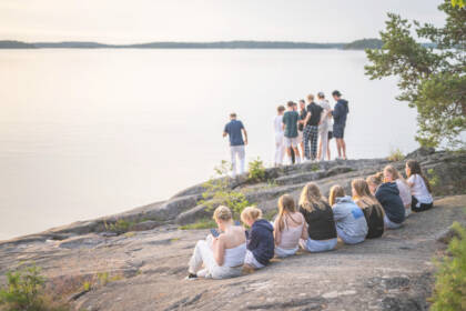 Iso määrä nuoria istuskelee ja seisoo rantakallioilla.