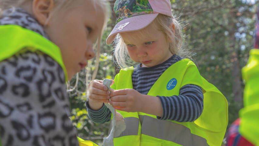Pikkutyttö leikkii muovailuvahalla pihalla.