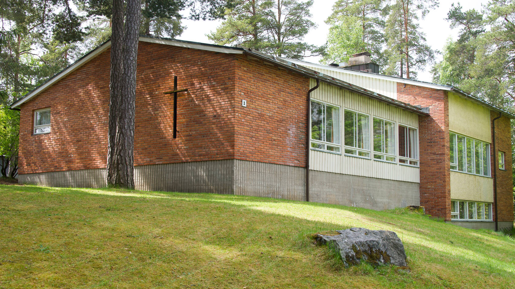 Punatiilinen rakennus rinteessä, ulkoseinällä risti.