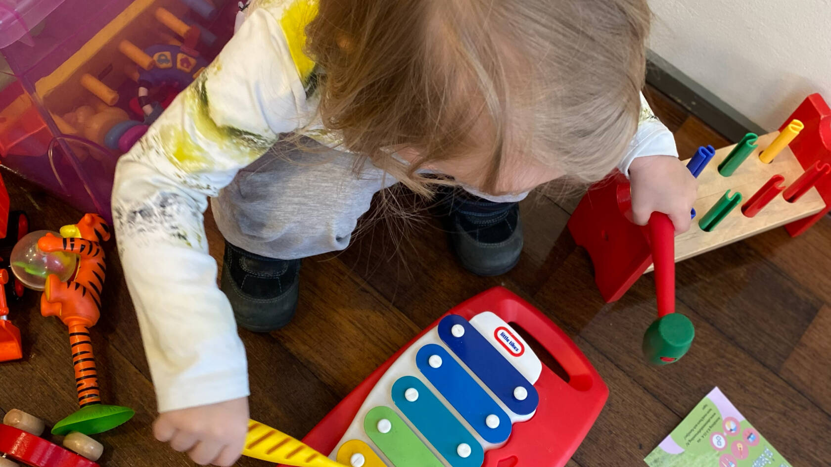 En liten flicka sitter på huk och spelar på en xylofon.