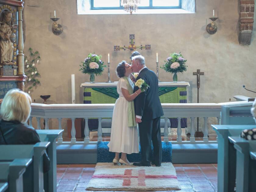 Brudparet kysser varandra framför altaret.