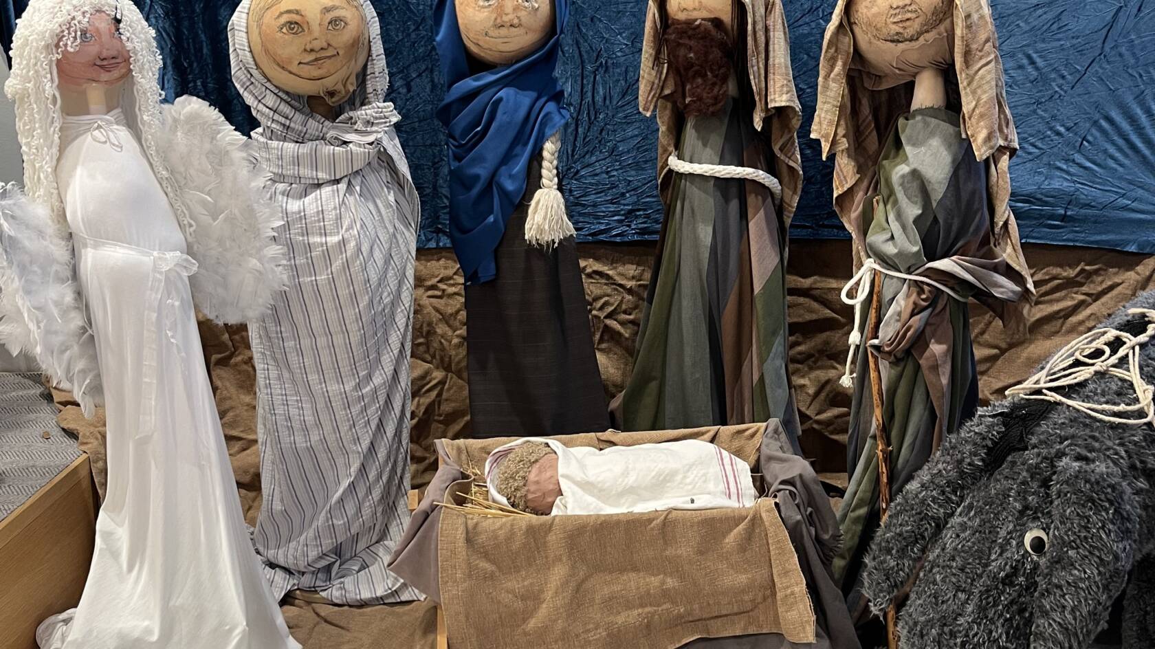 Fem handgjorda dockor och en åsna vid julkrubban.