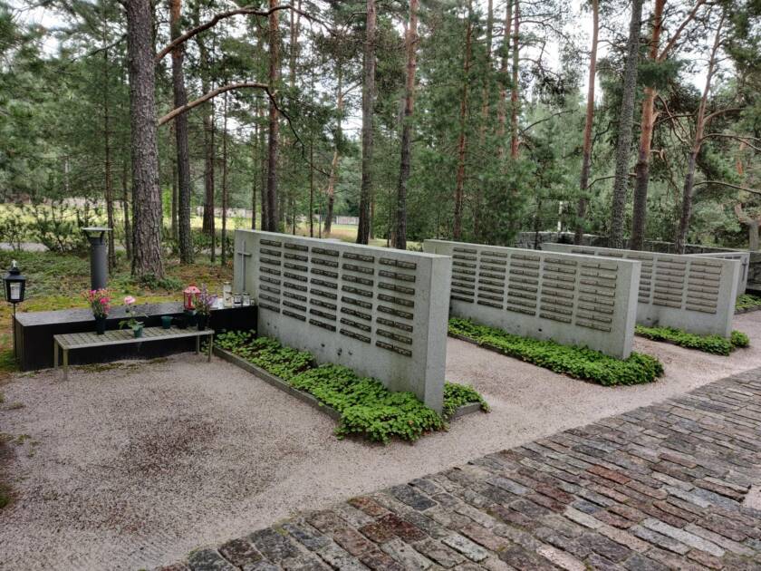 Kolme suurta kivipaatta, joihin on kiinnitetty pieniä metallilaattoja. Laatoissa on nimiä.