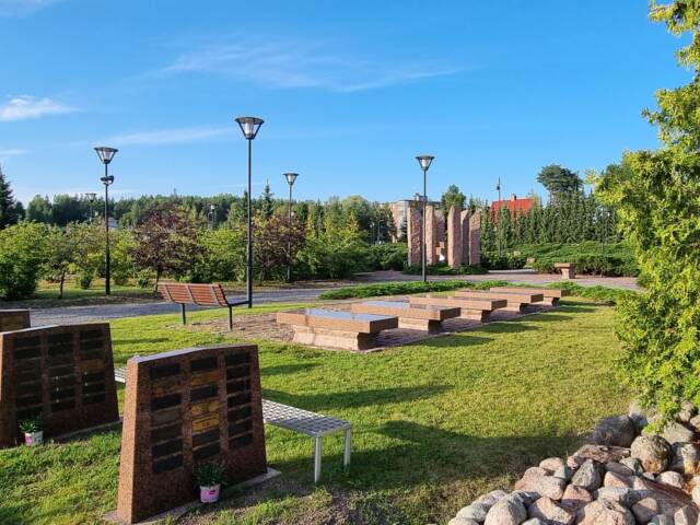Hautausmaan aukio, jolla on kolme pystyä kivipaatta, joissa on metallilaattoja, viisi vaakatasossa olevaa kivipaatta sekä kivistä tehty kehä, jonka sisällä on risti.