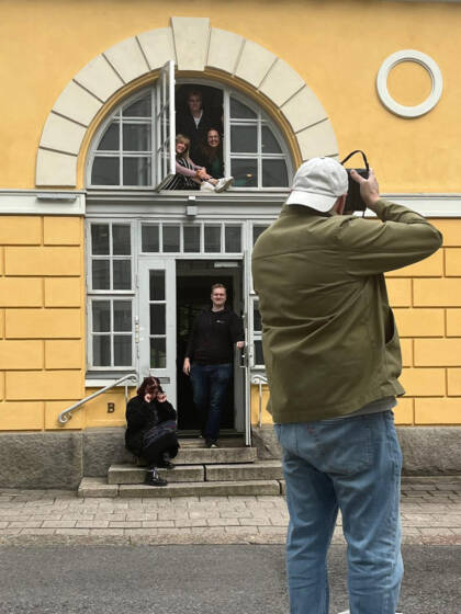 Valokuvaaja kuvaa ihmisiä rakennuksen ovella
