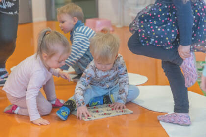 Pienet lapset tekevät palapeliä lattialla.