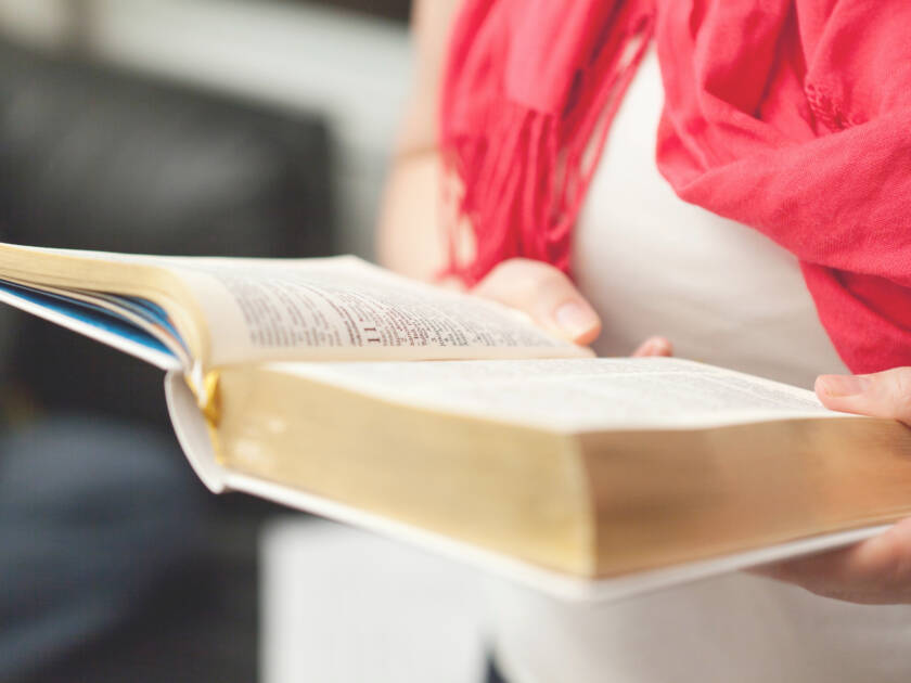 Kvinnan håller en bibel i händerna.