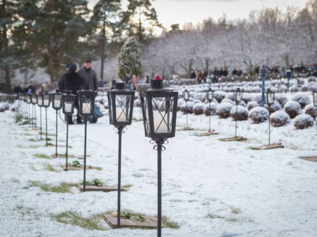 Sankarihautoja lumisessa maisemassa. Jokaisella haudalla on lyhty.