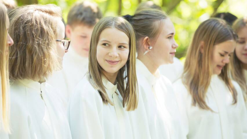 Nuoria rivissä albat päällä, Tyttö hymyilee pienesti vierustoverille.