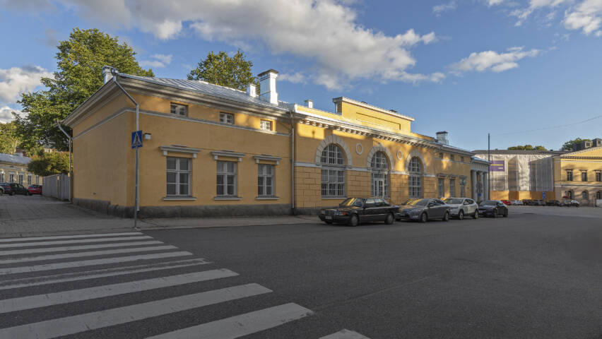 Keltainen kivirakennus, jonka keskellä on kolme isoa kaari-ikkunaa ja molemmilla sivuilla kolme ruutuikkunaa.