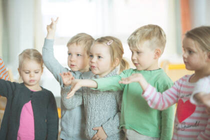 Viisi lasta seisoo rivissä ojennellen käsiään.