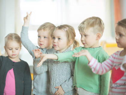 Viisi lasta seisoo rivissä ojennellen käsiään.