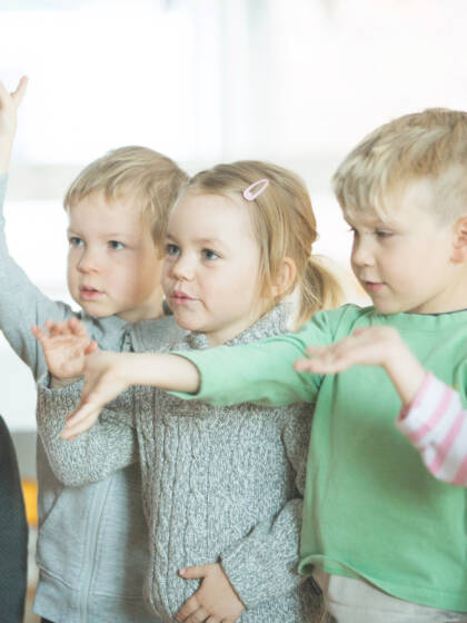 Viisi lasta seisoo rivissä ojennellen käsiään.