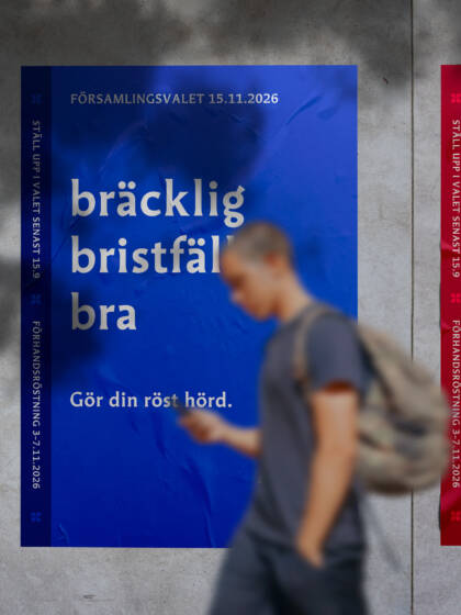 Tre affischer på en vägg med olika färger och texter. En person går förbi, i bakgrunden syns en röd, blå och grön affisch.