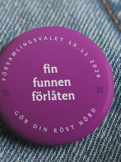 Lila knapp på denimtyg, texten "fin funnen förlåten" och datumet 15.11.2026.