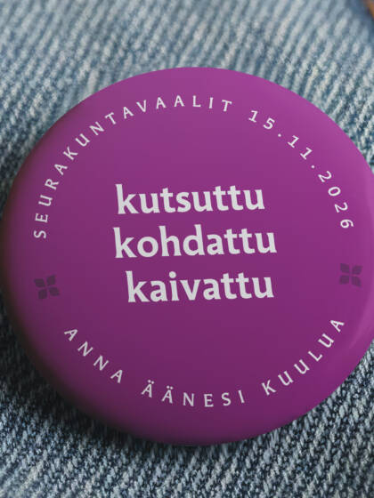 Violetti rintamerkki farkkukankaalla, teksti "kutsuttu, kohdattu, kaivattu" ja päivämäärä "15.11.2026".
