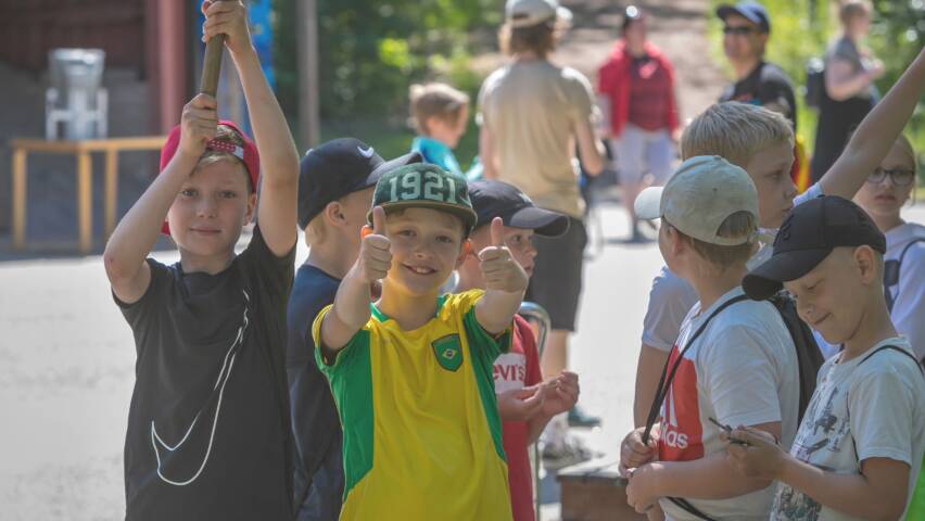 Ryhmä poikia seisoskelee pihalla. Yksi pojista näyttää peukkuja.