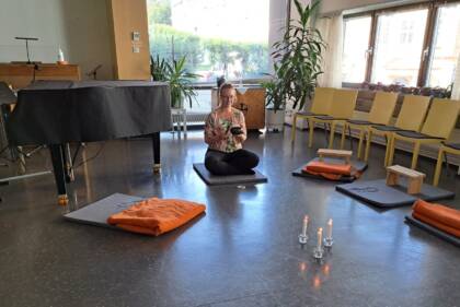 Meditationsledare sitter pä gålvet i Aurelia Musiksalen