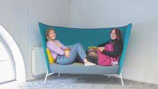Nuoria aikuisia istuu sohvalla hymyillen
