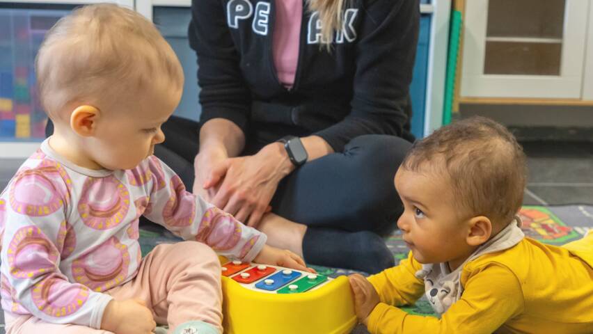 Kaksi vauvaa tutustuu toisiinsa lattialla leikkien.