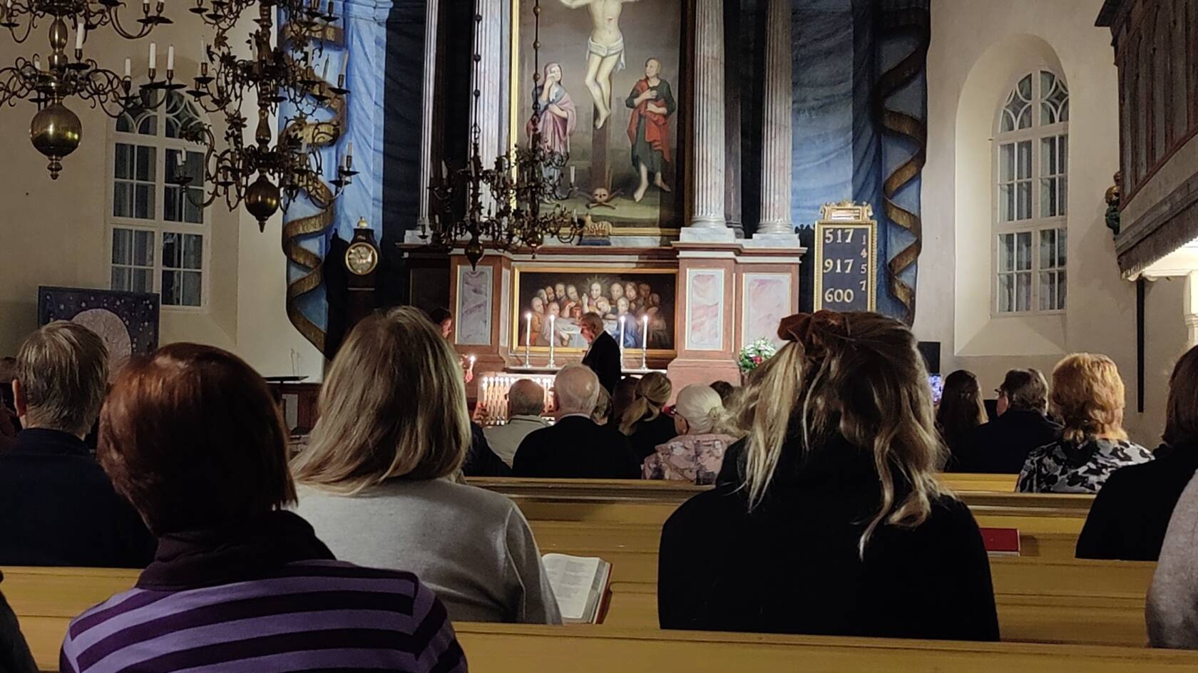 Kynttilöin valaistu hämärä kirkkosali.
