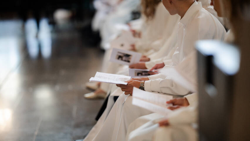 Konfirmander sittande i rad i kyrkbänken.
