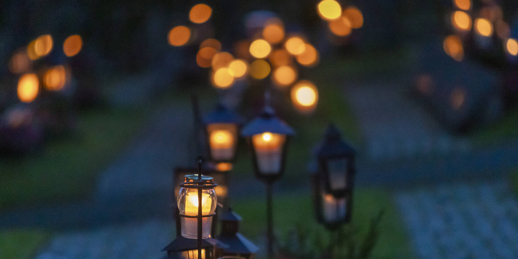 Kynttilöitä hämärtyvällä hautausmaalla.